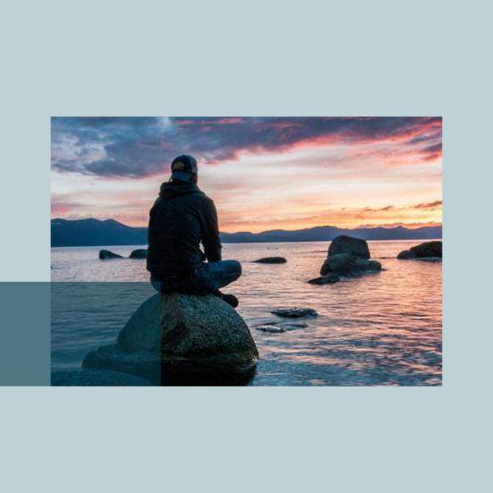 Foto af en person, som sidder på en sten i havet og mediterer