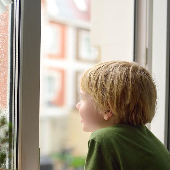Dreng kigger ud af vinduer på regnen