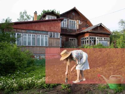 Kvinde graver i jorden med en skovl foran et gammelt hus