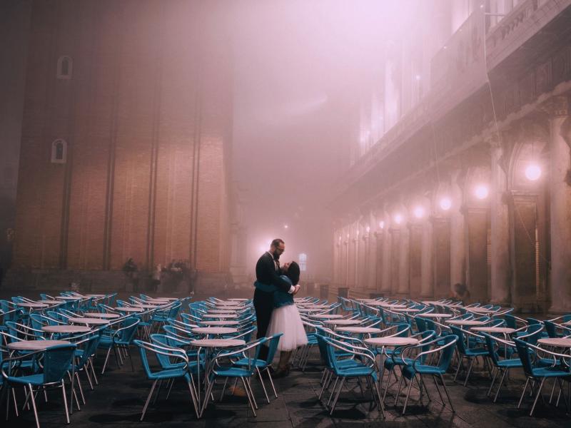 Par, der holder om hinanden midt imellem en masse caféborde og stole
