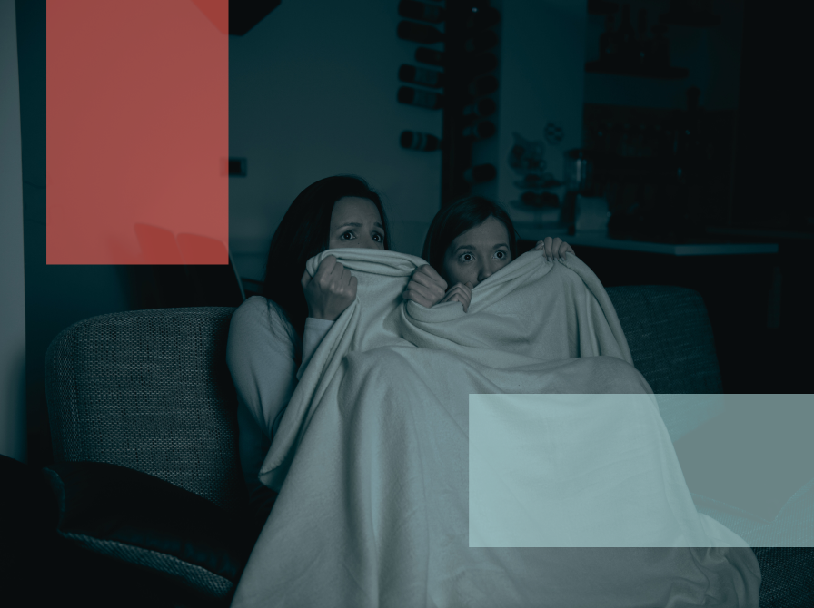 to piger gemmer sig bag tæppe, mens de ser uhyggelig film