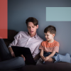 Far læser på iPad sammen med dreng